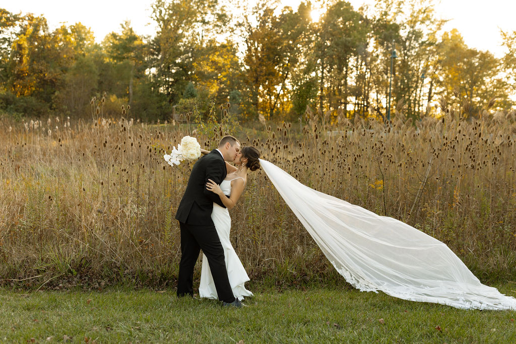 Bride and groom kissing in the meadow at The Estate