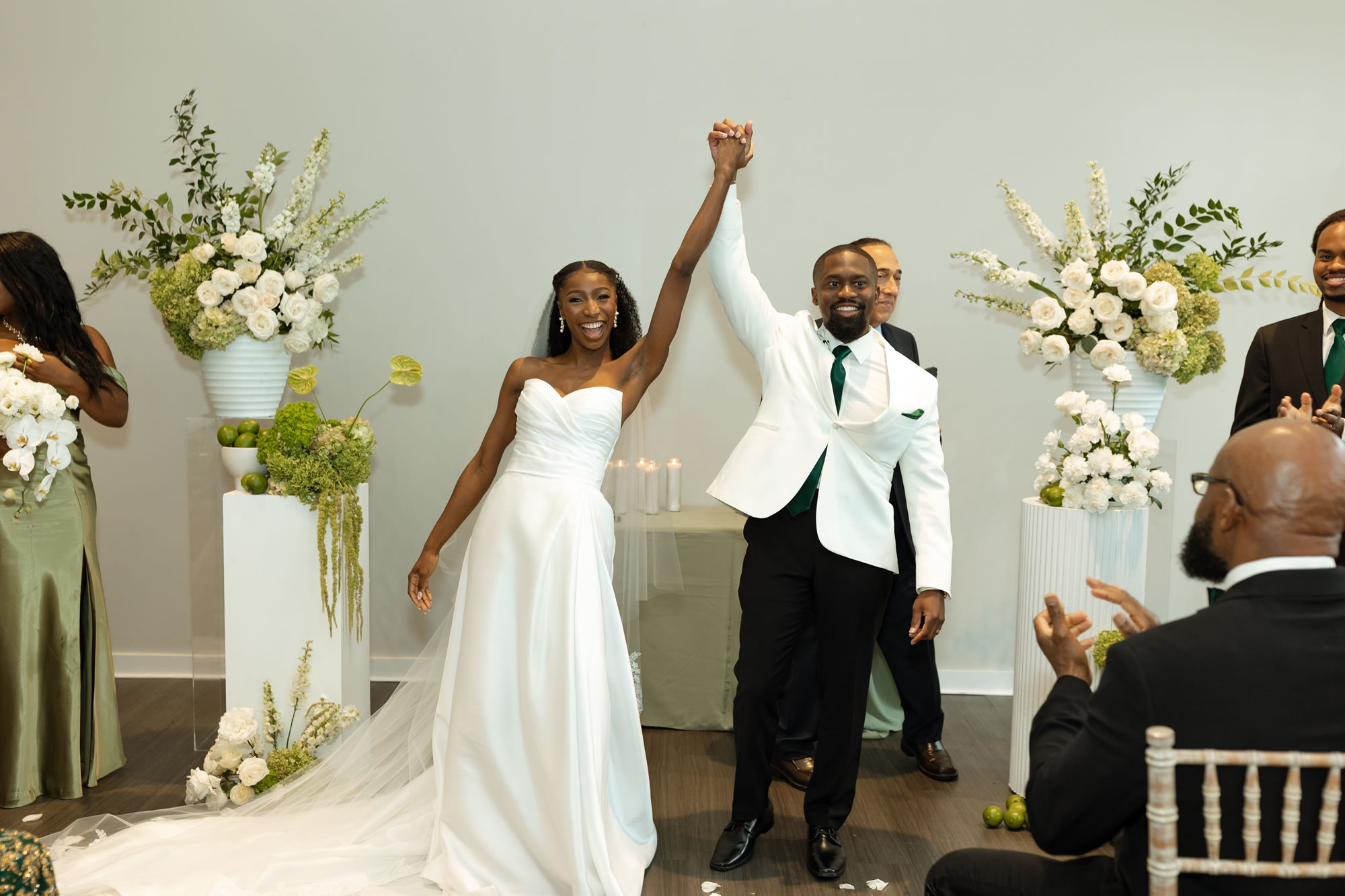 Bride and groom holding raised hands celebrating after ceremony at The Estate