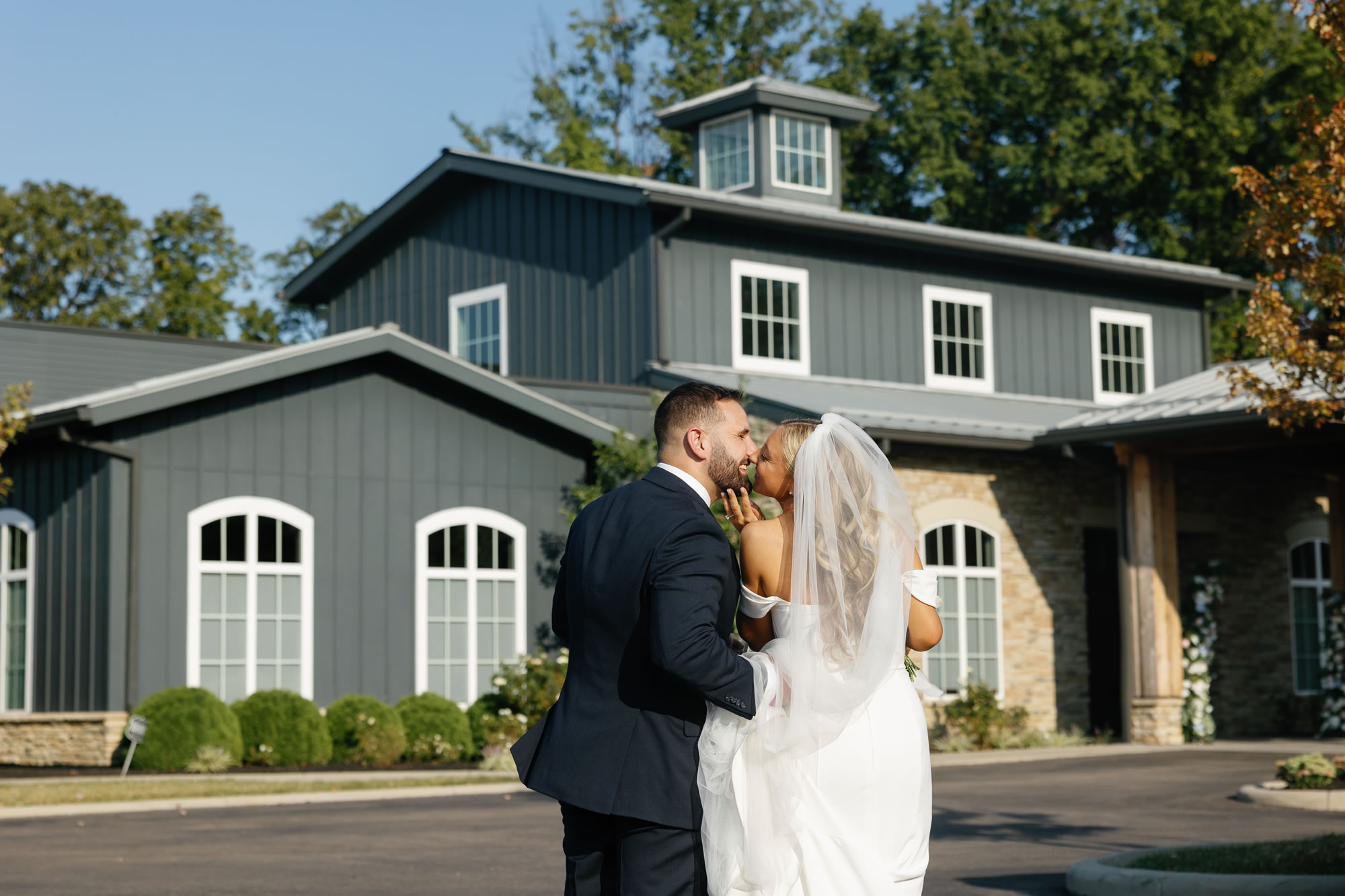 Bride and groom kissing outside on entryway drive at The Estate