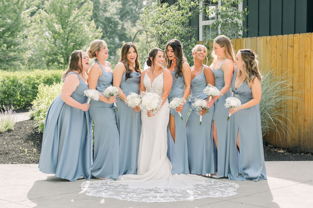 Bride in white surrounded by bridesmaids in light blue dresses